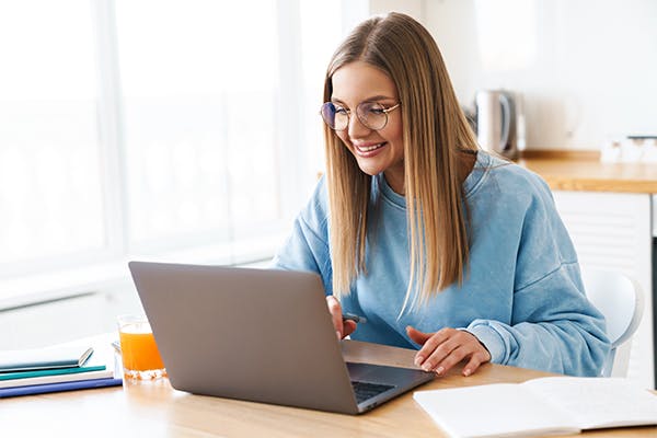 Image-of-cheerful-charming-woman-in-eyeglasses-smiling-while-working-with-laptop-at-home
